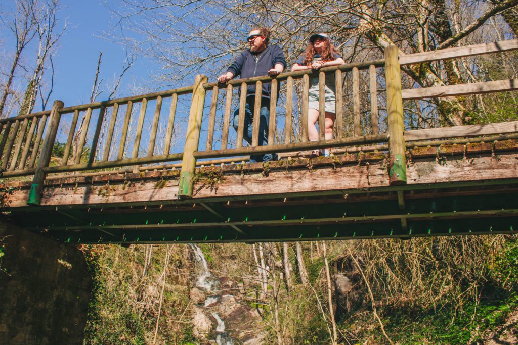 pere et fille sur un pont en bois devant une cascades dans les gorges de Narvau, en bourgogne.