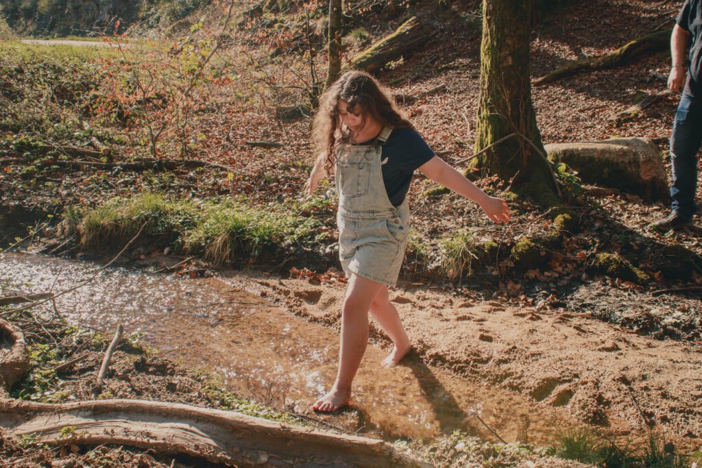 Petite fille qui se baigne les pieds dans un ruisseau près du lac de chaumeçon. séance photo famille Auxerre.