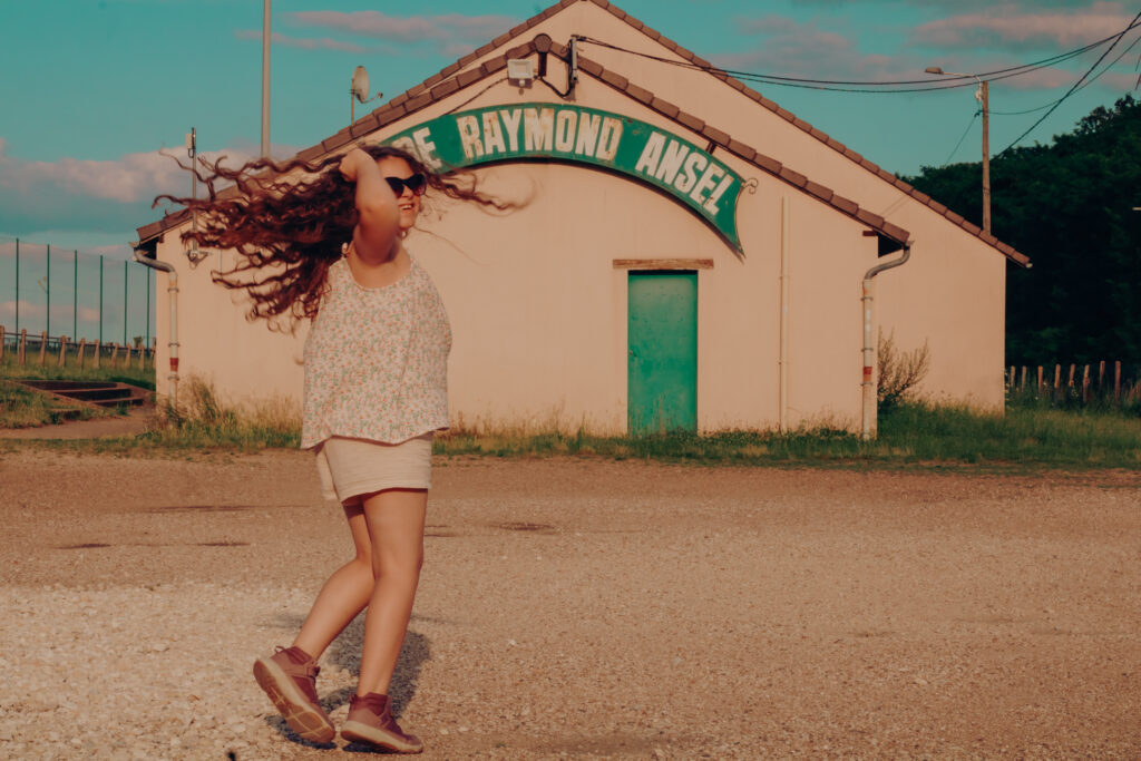 Petite fille tournant joyeusement sur elle-même au soleil, ses cheveux flottant dans les airs, en pleine campagne près d’Auxerre, en Bourgogne.