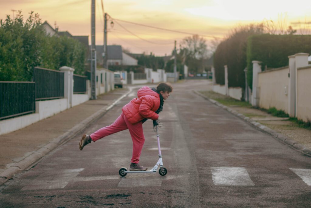 Petite fille traversant un passage piéton en trottinette. Photographe famille Auxerre.
