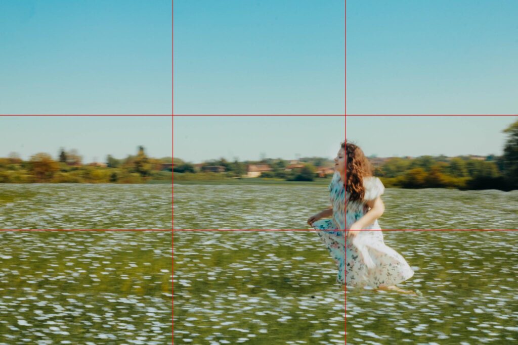 Fille courant dans un champ de fleurs sous un ciel bleu, capturée selon la règle des tiers pour illustrer la composition photo en mouvement.