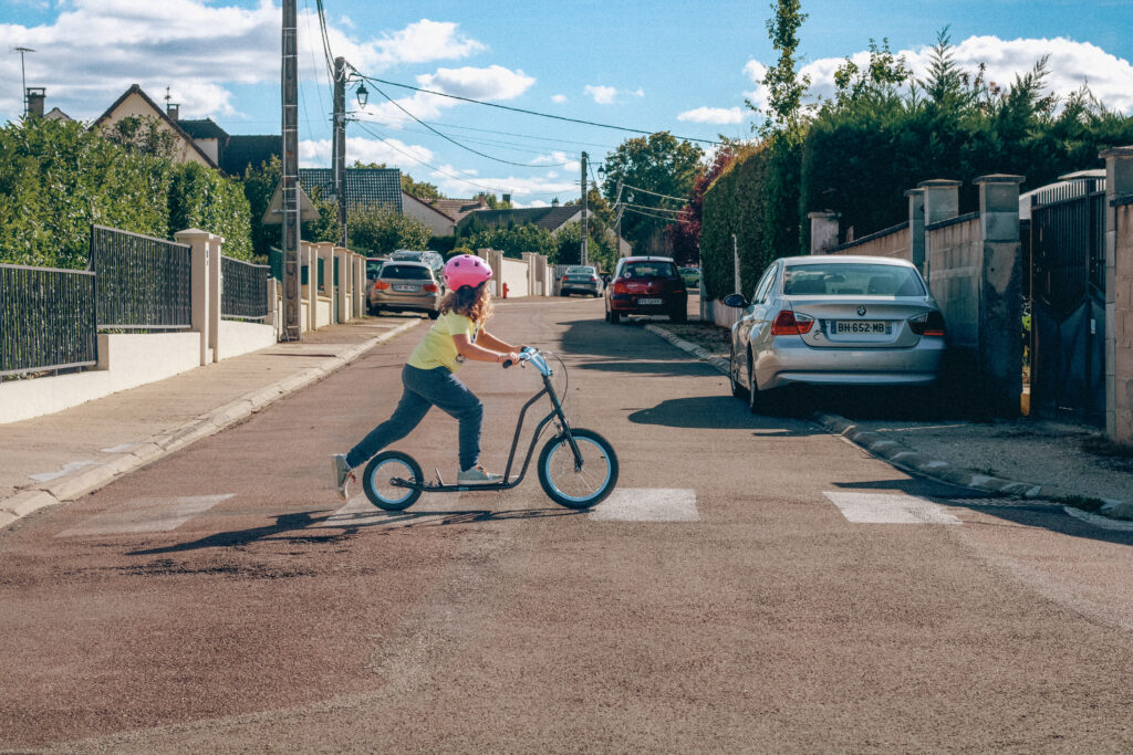 Petite fille traversant un passage piéton en trottinette