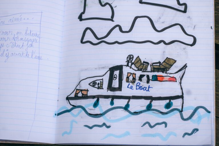 Dessin d’un bateau réalisé par un enfant pendant une balade au bord de l’eau, carnet de vacances créatif
