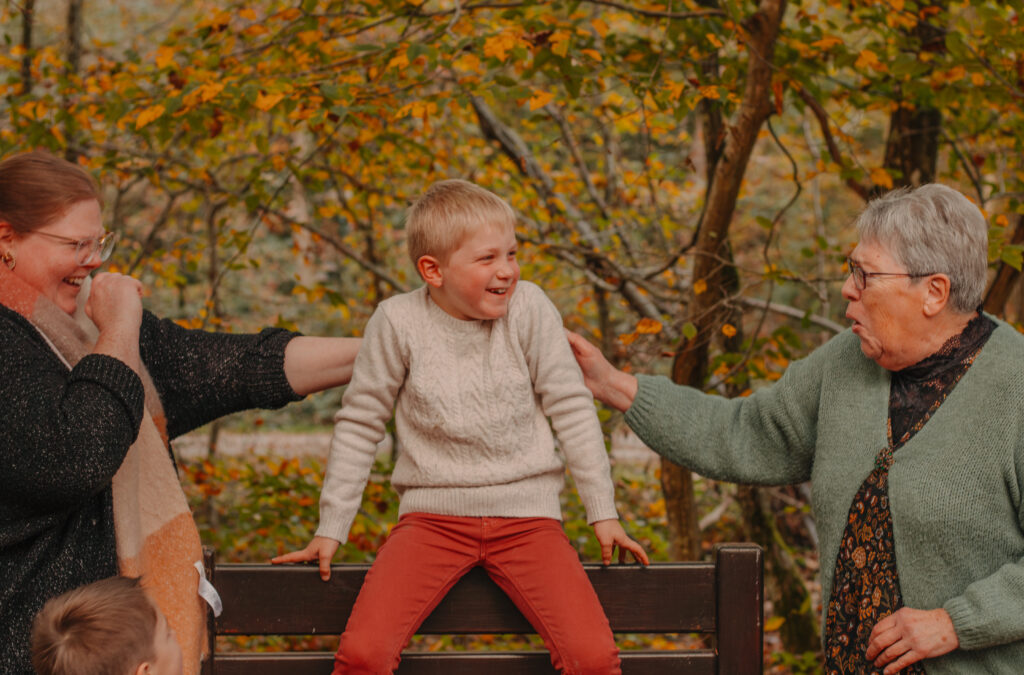 Petit garçon riant avec sa mère et sa grand-mère, moment de complicité familiale et d’émotion partagée.
