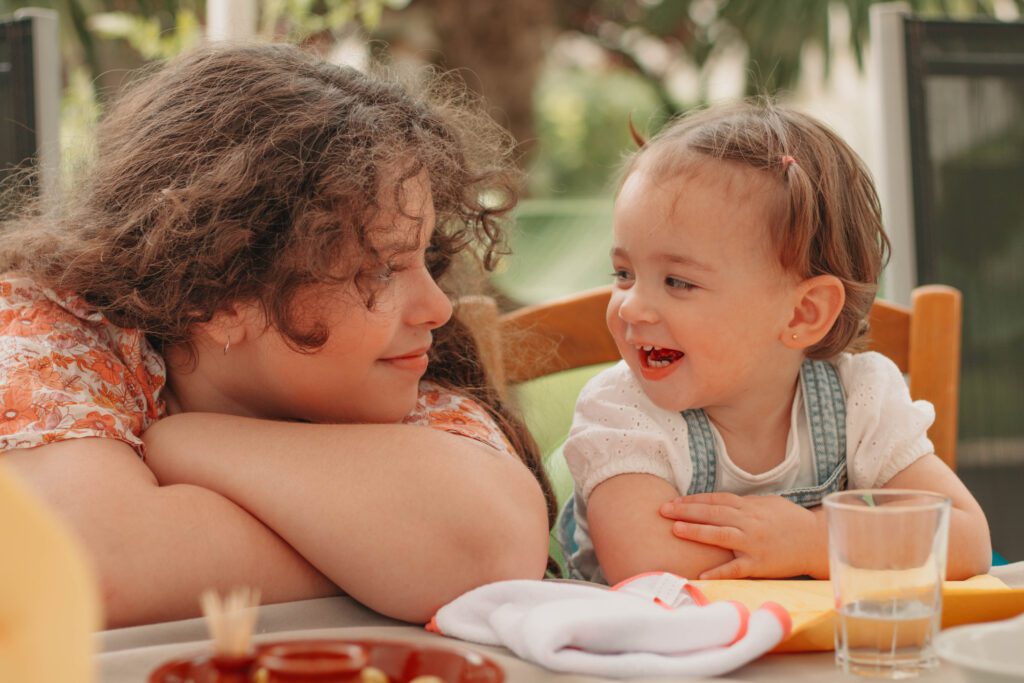 Moment de complicité entre deux cousines, regard tendre et sourires spontanés, photo professionnelle capturant l’émotion authentique.