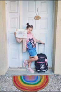 Petite fille posant devant la porte le jour de sa rentrée en CE1, exemple de photos de rentrée des classes