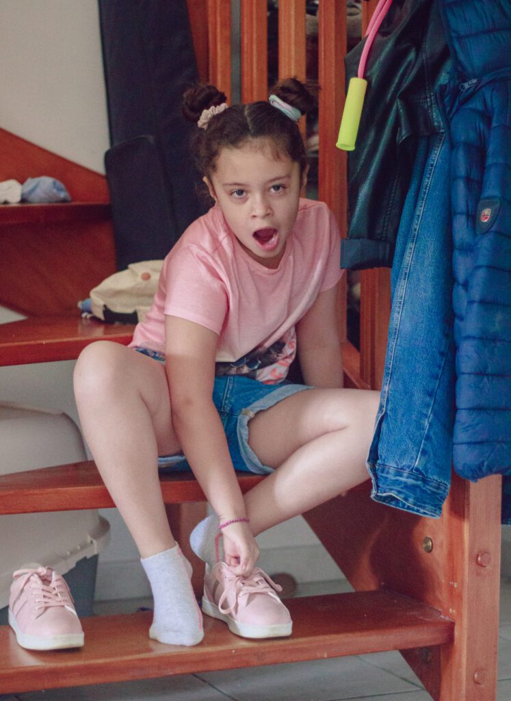 Petite fille qui baille en enfilant ses chaussures le matin de la rentrée des classes