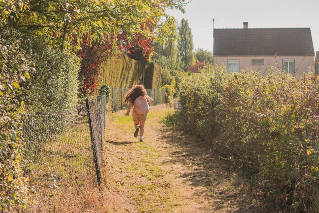 photos de rentrée des classes, petite fille cartable sur le dos sur le chemin de l'école.