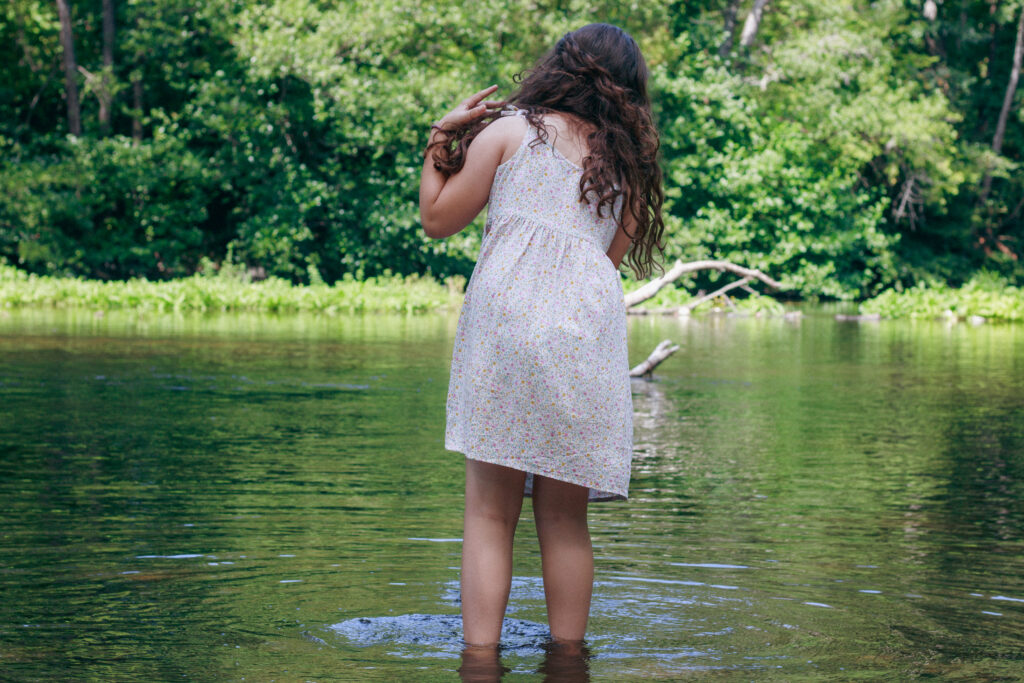 Petite fille qui se trempe les pieds au parc des iles de Vermenton, lors d'une séance photos dans les plus beaux villages de l'yonne