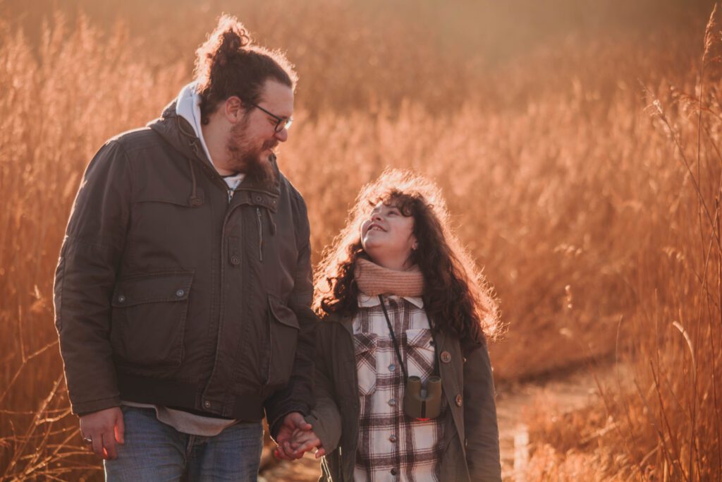 un père et sa fille se promènent mains dans la main en automne.
