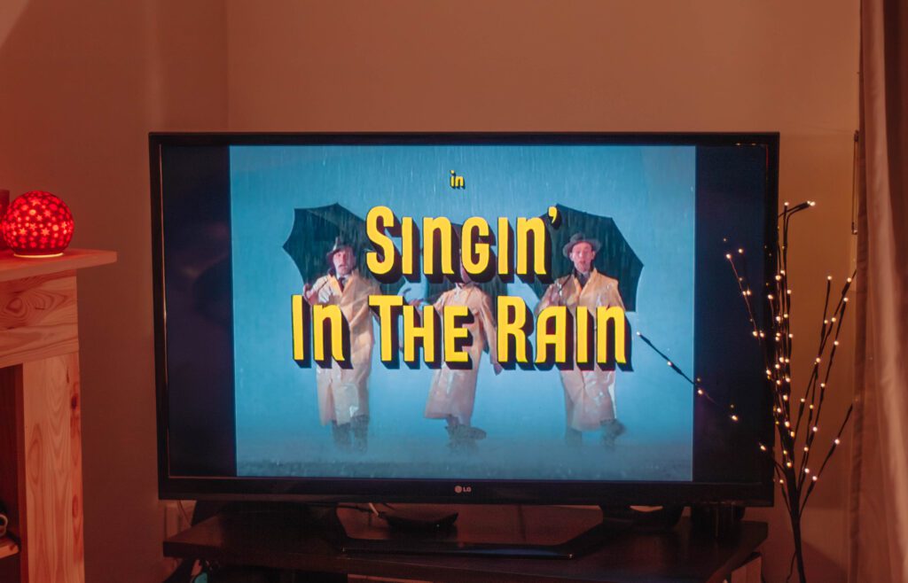 Ambiance cosy de Noël avec un écran où apparaît le film Chantons sous la pluie