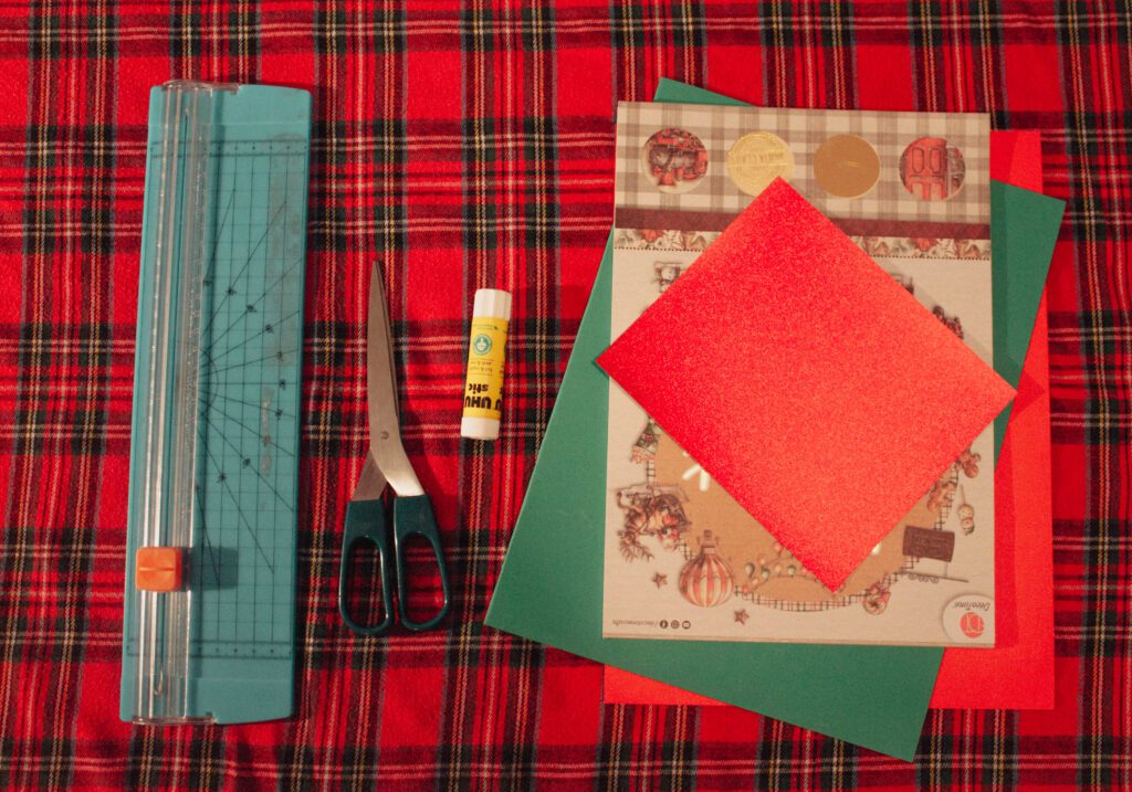 Matériel nécessaire pour fabriquer une guirlande de noël en papier : papiers colorés, colle et ciseaux.