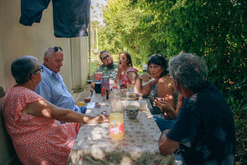 Photo d’un groupe de personnes partageant un repas en terrasse dans une ambiance conviviale et printanière.