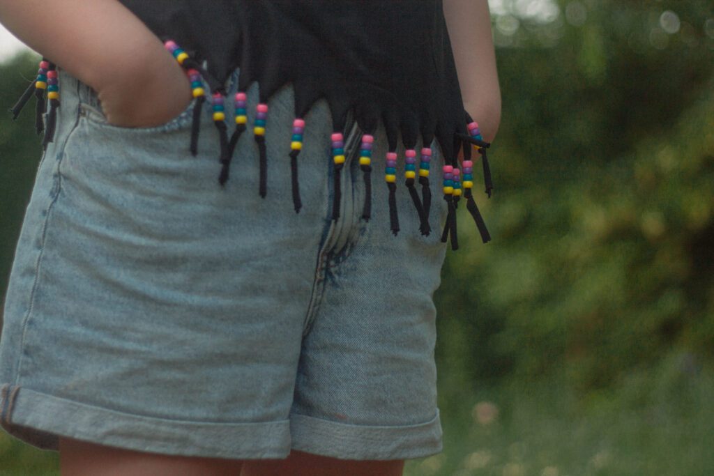 Détail d’un t-shirt à franges perlées DIY porté par une enfant, création réalisée avec des perles